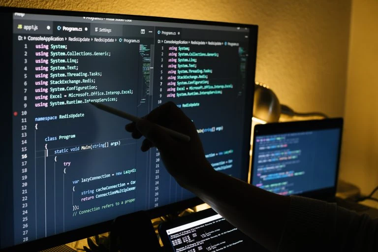 Developer coding at night pointing at screen with code — Swonie Custom Software
